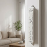 Elegant white Keter mezuzah case mounted inside a doorway reveal, emphasizing traditional design and subtle decorative accents.