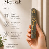 Person holding the exact source Jerusalem stone Tree of Life Gray mezuzah, showcasing its craftsmanship and materials in a natural setting for a premium product feature.