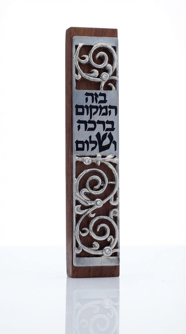 Dark mahogany wood mezuzah with pewter swirling design and blessing inscription, on a white studio background with soft reflection.