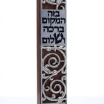 Dark mahogany wood mezuzah with pewter swirling design and blessing inscription, on a white studio background with soft reflection.